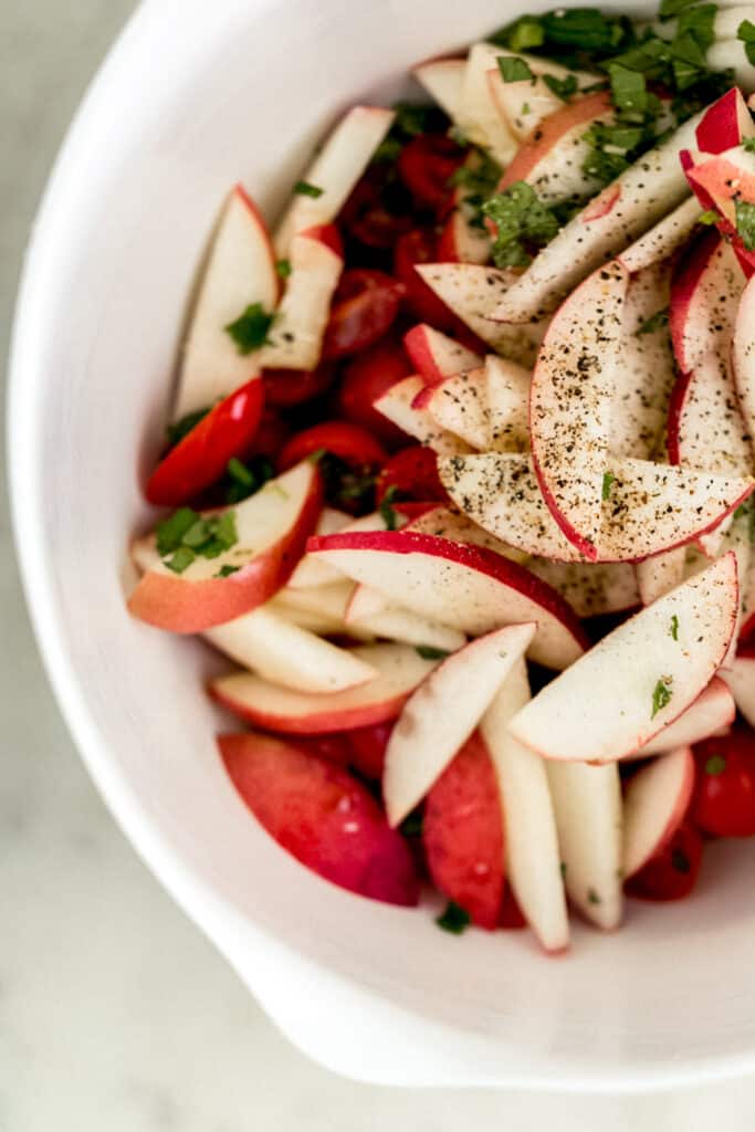 ingredients for tomato peach salad in large white mixing bowl 