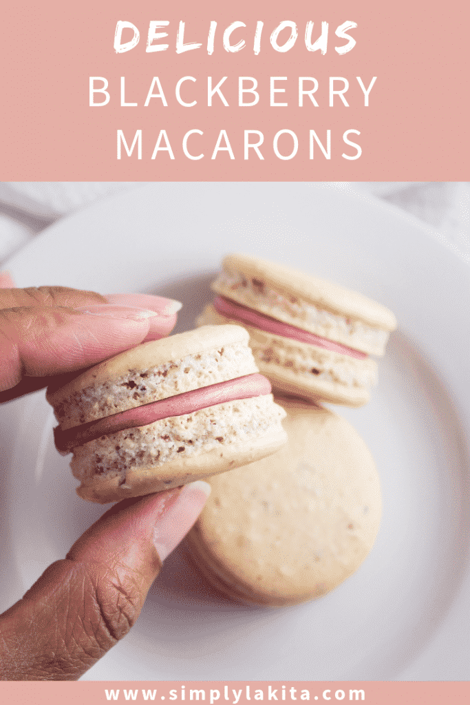 blackberry macarons being held by hand over plate