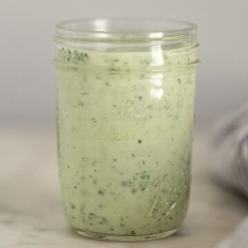 close up side view cilantro lime dressing in small glass jar