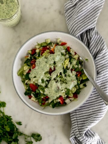 overhead view salad topped with cilantro lime dressing in bowl with fork.