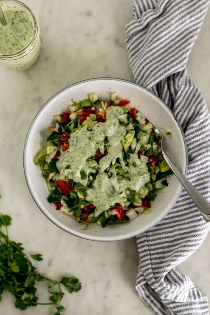 overhead view salad topped with cilantro lime dressing in bowl with fork. 