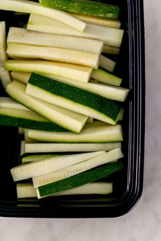 fresh zucchini in black container cut into the shape of fries 
