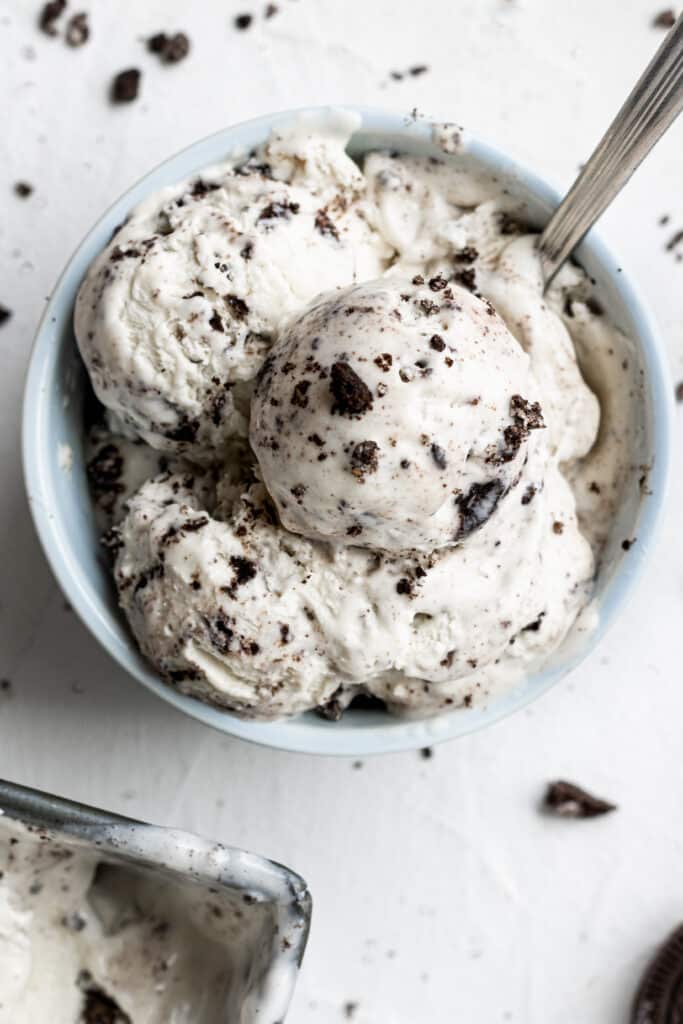 cookies and cream ice cream in a small bowl beside a spoon. 