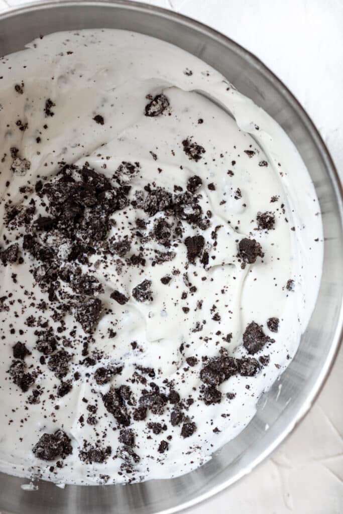 sandwich cookies added to ice cream mixture in mixing bowl