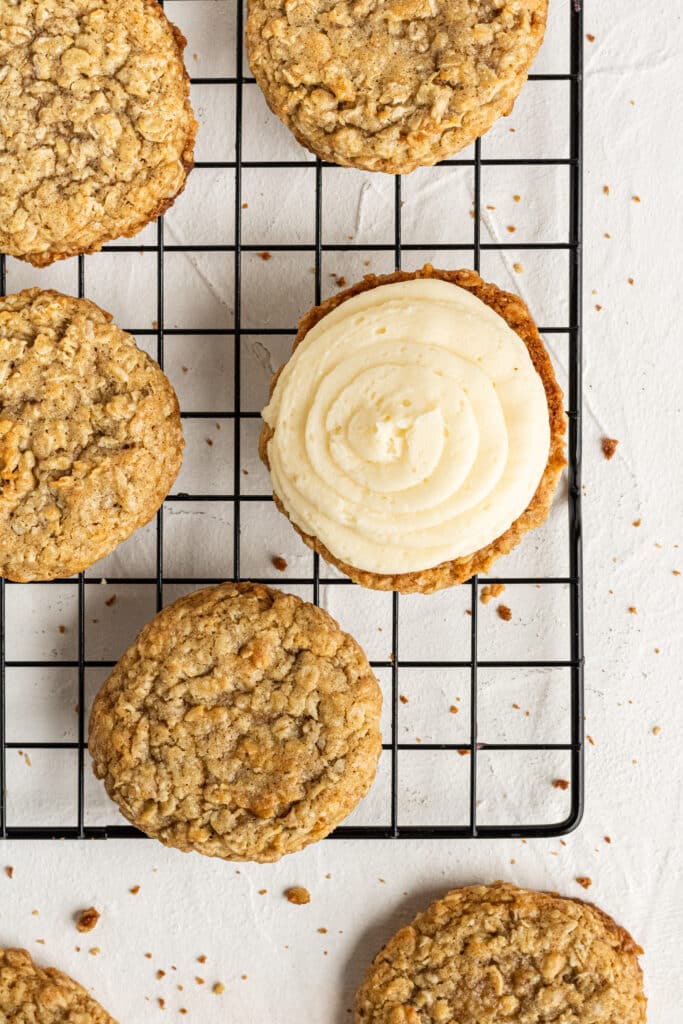 oatmeal cookies on cooling rack with one cookie topped with cream filling. 