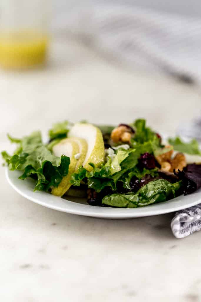 side view pear walnut salad on small white plate
