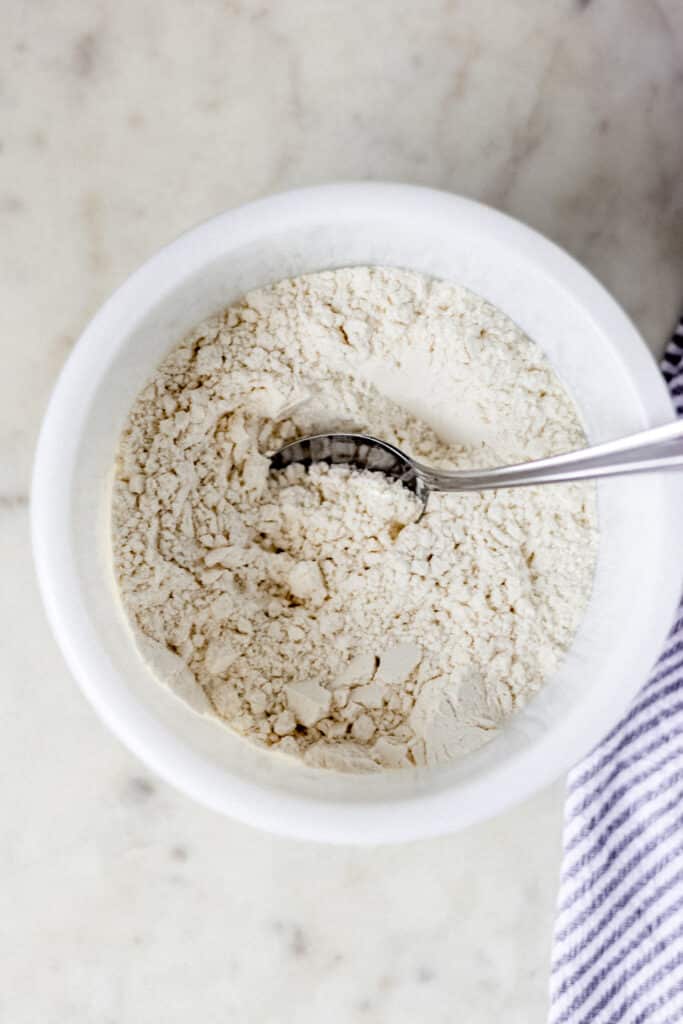 flour, baking soda, and cream of tartar in a white bowl with spoon