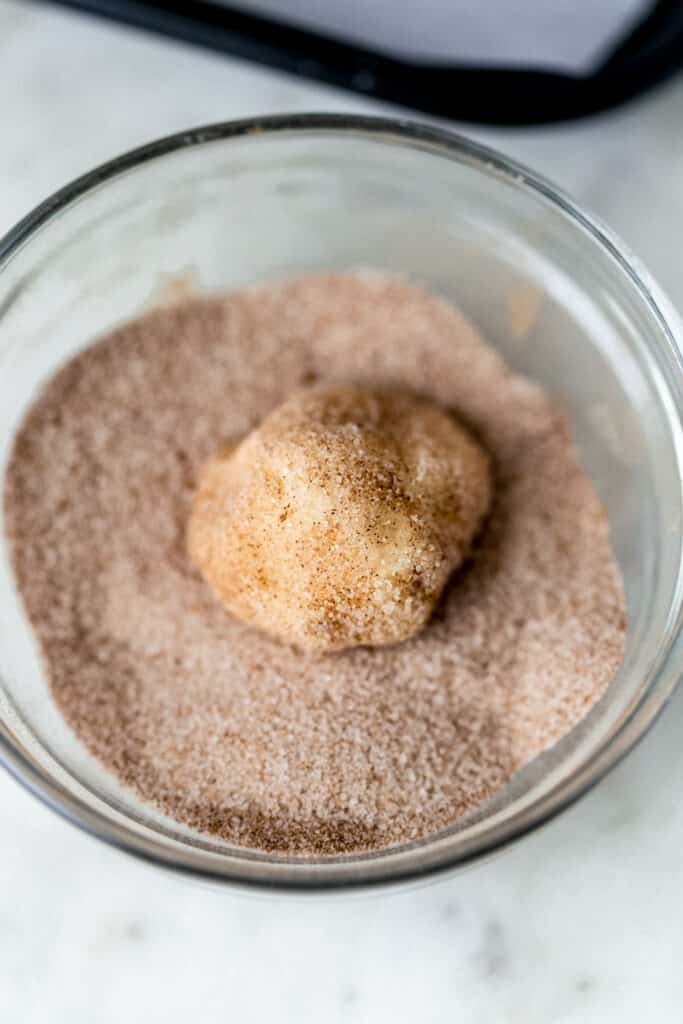 cinnamon sugar mixture in small bowl with cookie dough ball