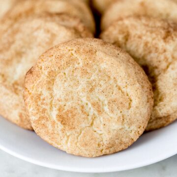 close up side view snickerdoodle cookies on a white plate