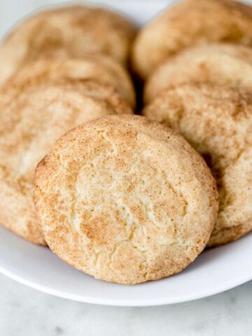 close up side view snickerdoodle cookies on a white plate
