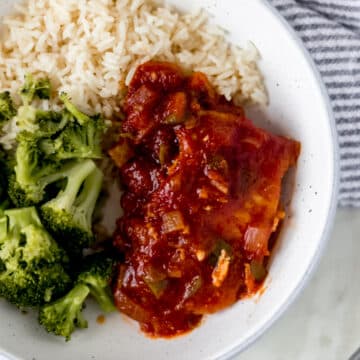 overhead view of shallow bowl of peachy salsa pork chops, rice, and broccoli with napkin