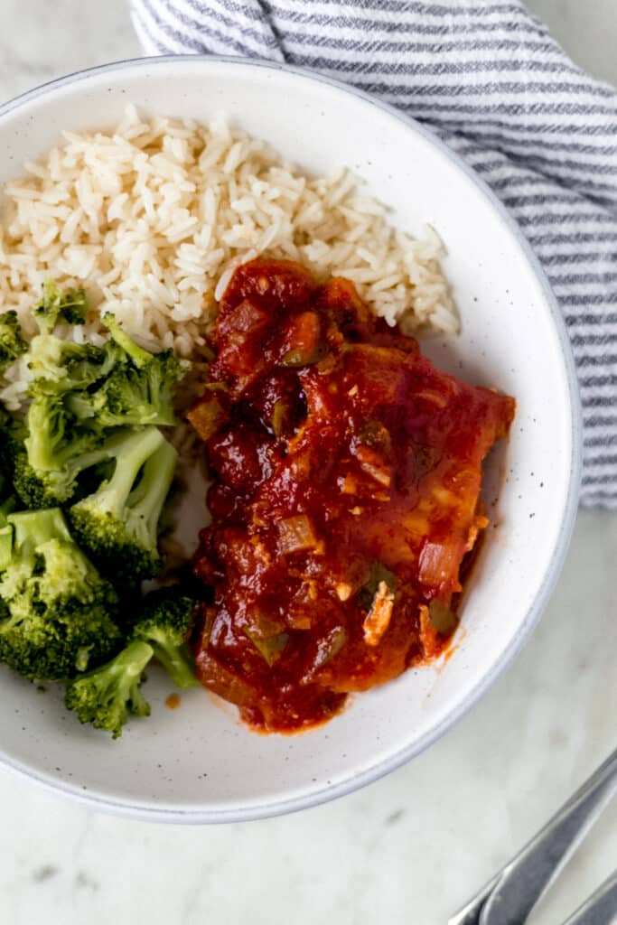 overhead view of shallow bowl of peachy salsa pork chops, rice, and broccoli with napkin