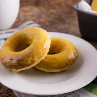 close up side view of two finished doughnuts on white plate