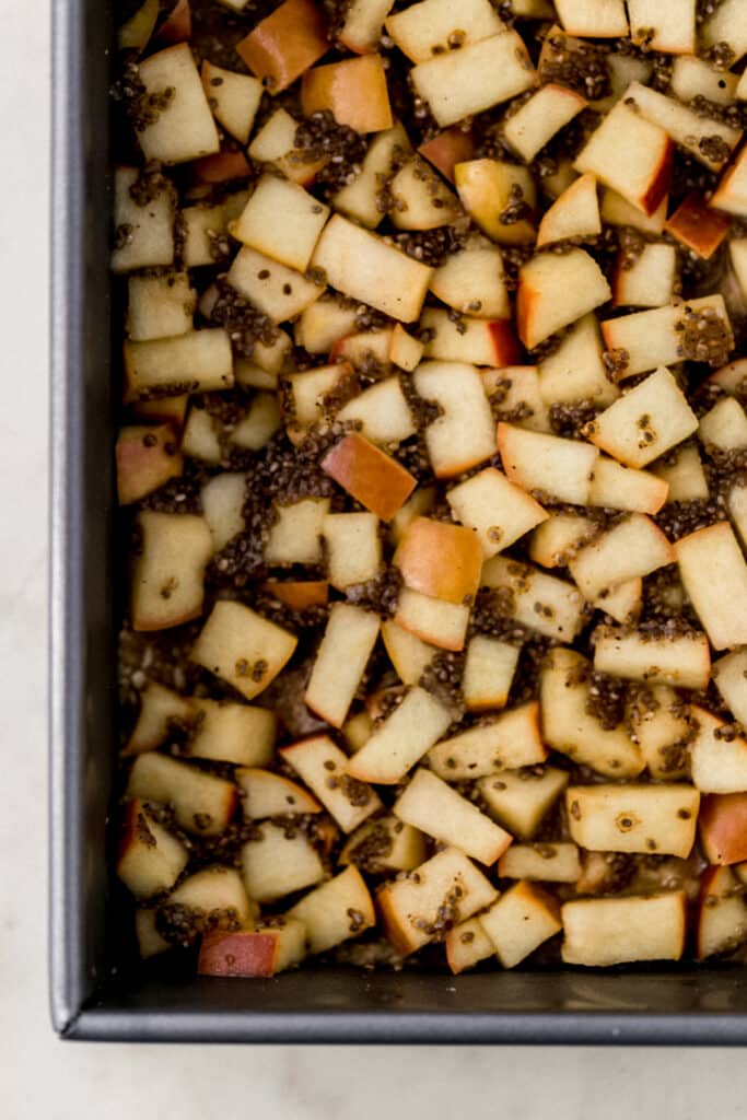 apple mixture added to the top of the crust mixture in a square baking dish.