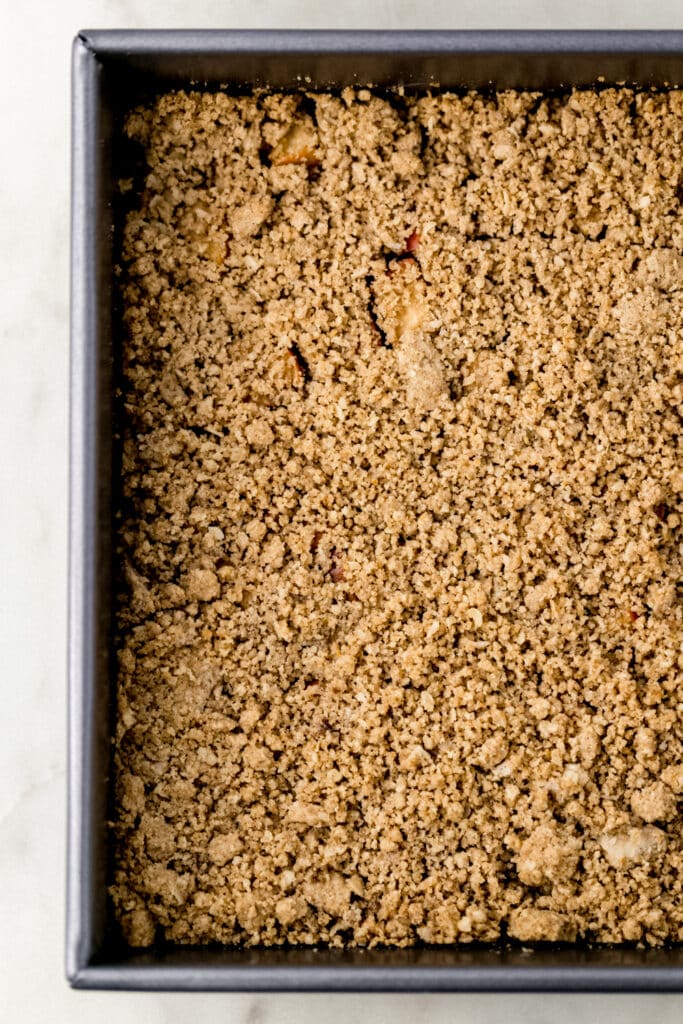 apple crumble bars in a square baking pan before baking.