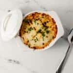 overhead view of finished pizza bowl beside the ramekin lid and spoon