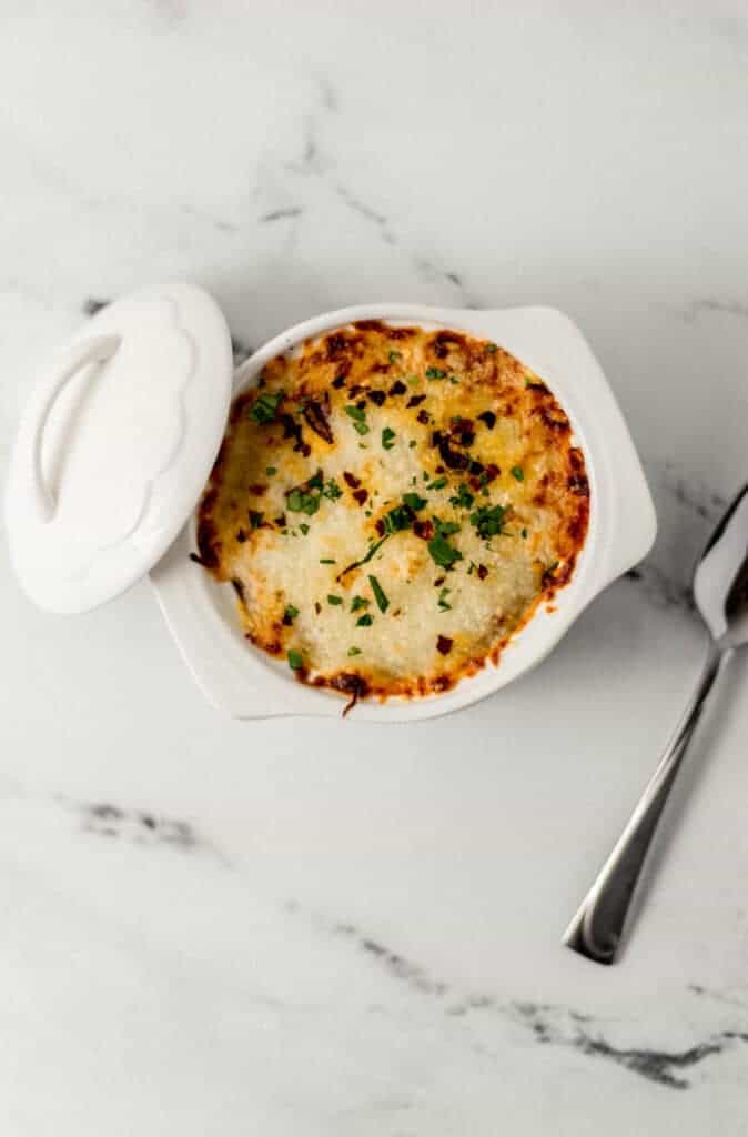 overhead view of finished pizza bowl beside the ramekin lid and spoon