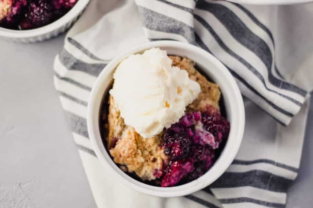 Overhead view cobbler in small white bowl topped with ice cream