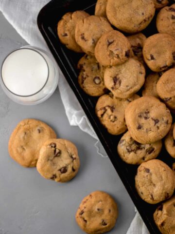 overhead view of cookies on sheet pan beside a cup of milk