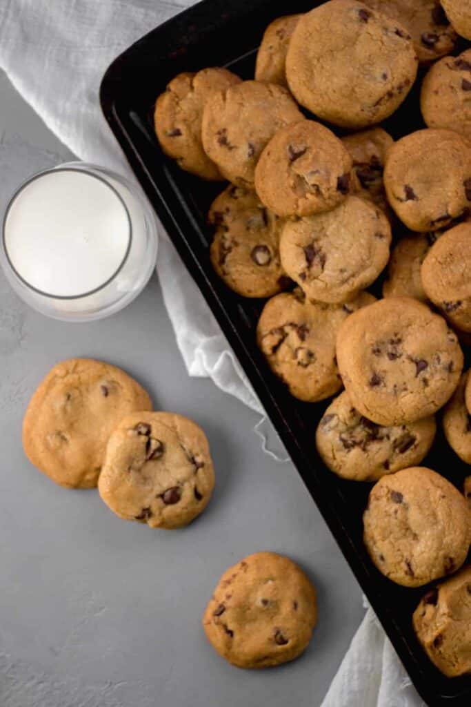 Overhead view Coconut Oil Chocolate Chip Cookies on a sheet pan by a glass of milk