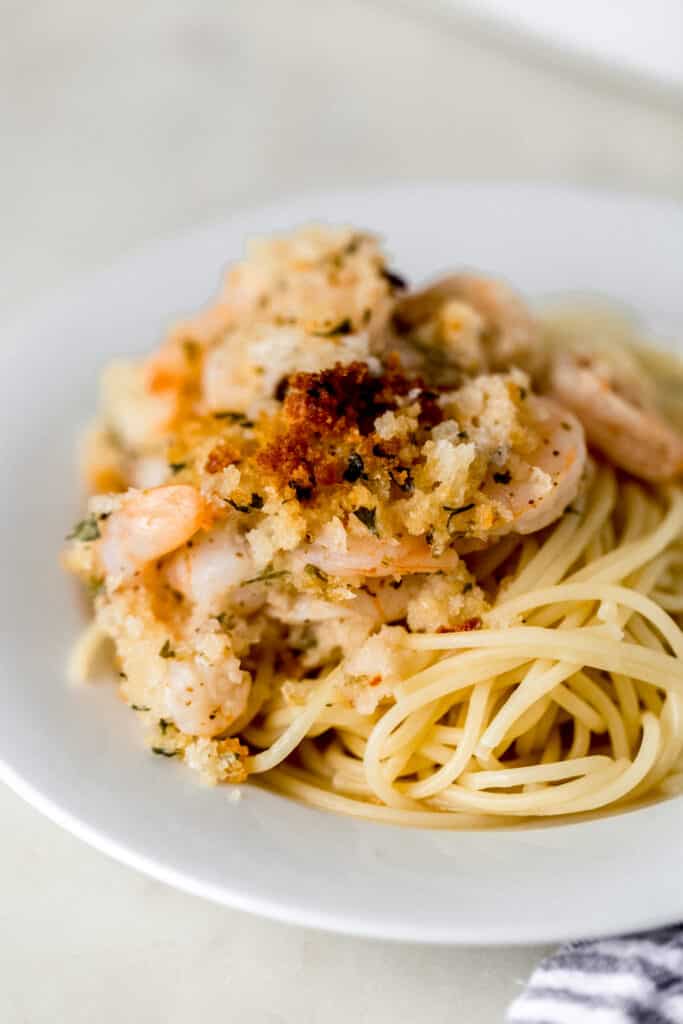 small white plate with baked shrimp scampi over pasta