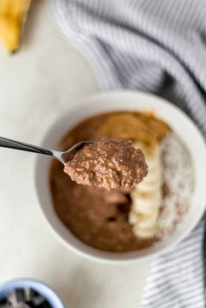 hand holding spoon with chocolate mocha overnight oats on it over bowl