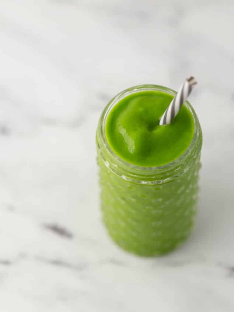 green smoothie in glass with straw