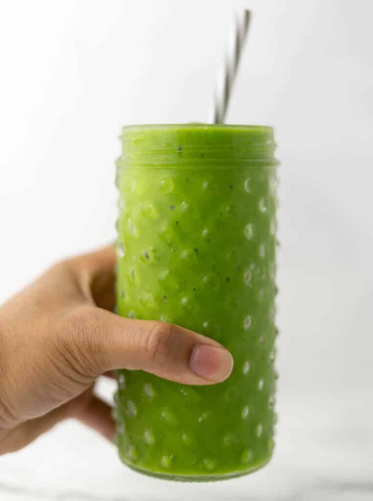 hand holding glass with straw and smoothie in it. 