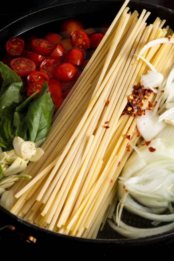 all of the ingredients to make one pot pasta combined in a large black skillet. 