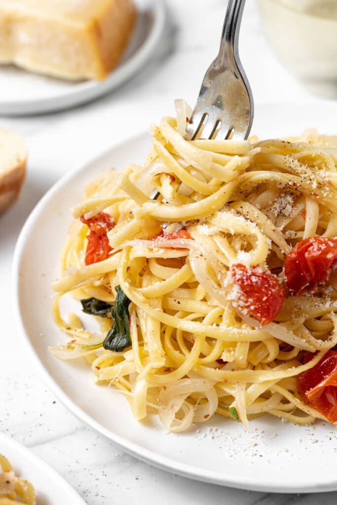 close up side view serving on pasta on white plate with fork in it. 