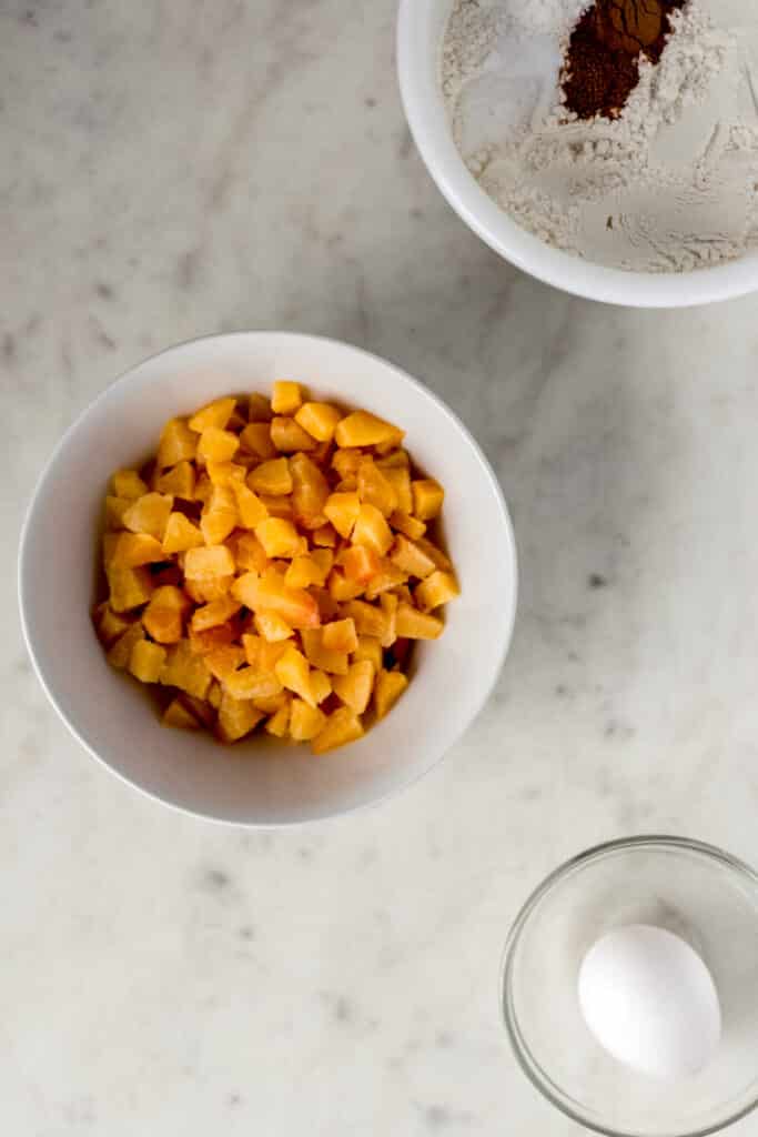 ingredients for peach cobbler muffins in three bowls