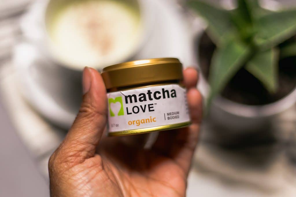 hand holding matcha powder for matcha latte 