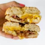 hand holding breakfast bagel sandwich
