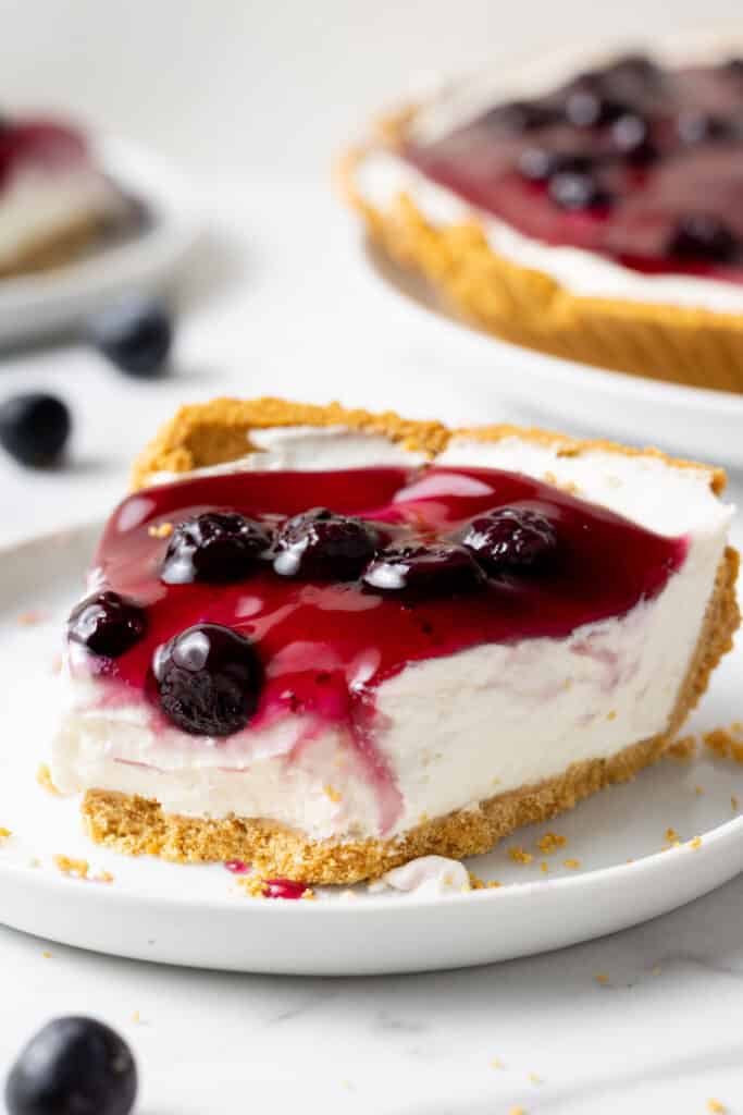 slice of blueberry cheesecake on white plate with a bite out of it. 