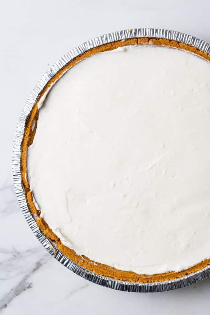 overhead view of filling added to pie crust to make blueberry cheesecake. 