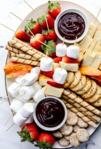 Overhead view of dessert board with chocolate fondue dippers on it on marble surface.