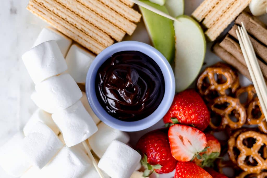 overhead view of chocolate dipping sauce in bowl on epic dessert board
