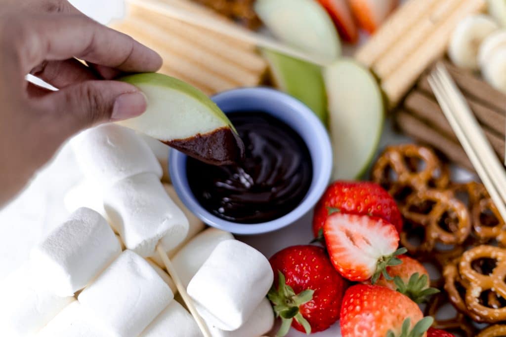 close-up side view chocolate dipping sauce in bowl on epic dessert board