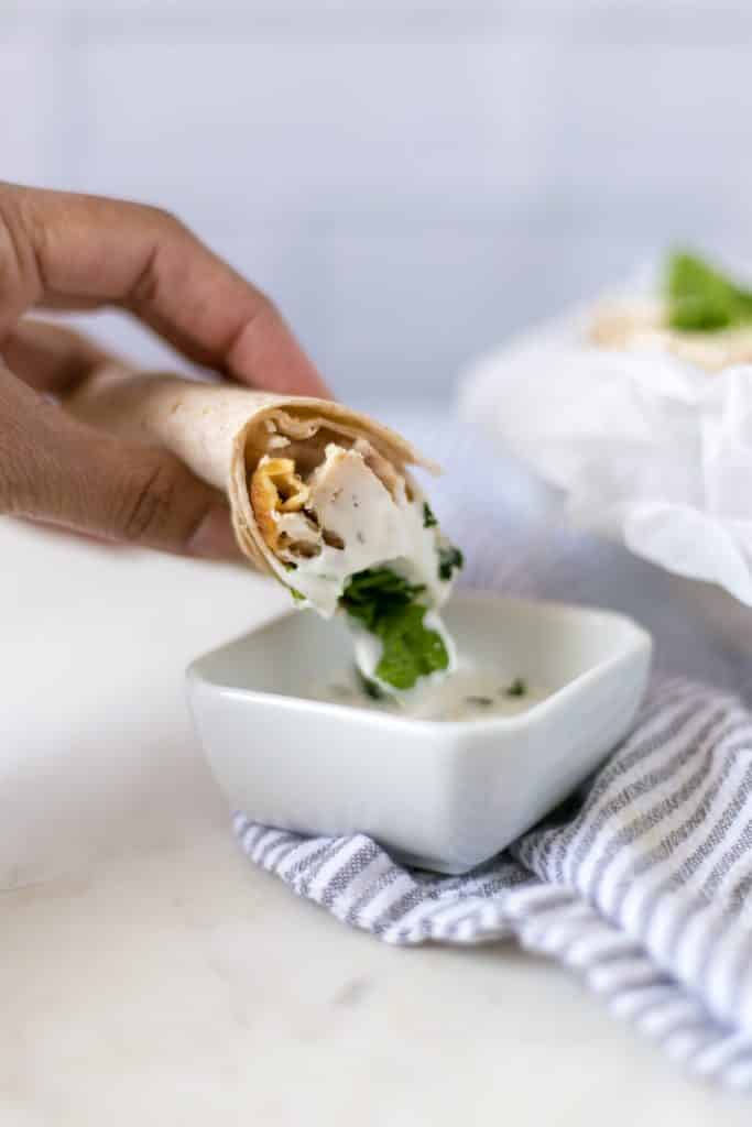 hand dipping chicken ranch wrap in ranch dressing