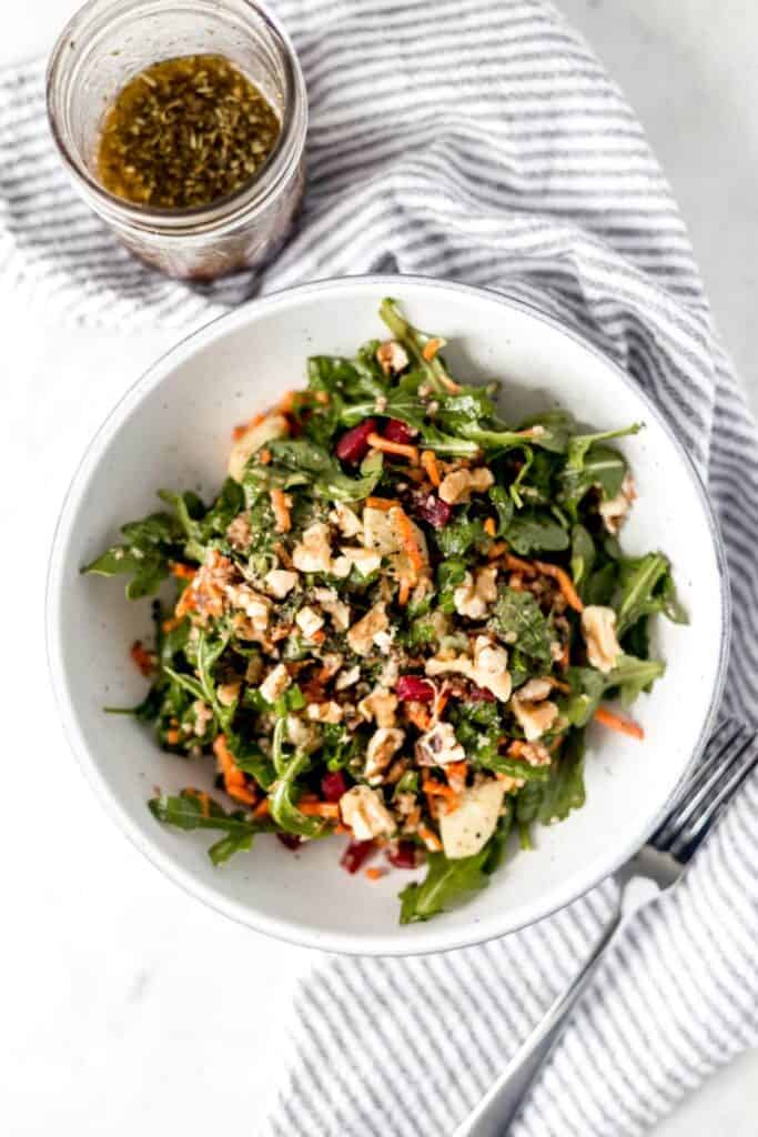 overhead shot of salad in a bowl with a small jar of dressing on the side