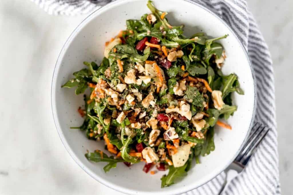 bowl full of salad with fork and napkin on the side