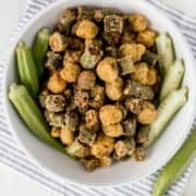 Overhead view of fresh and fried okra in a bowl on a cloth napkin.