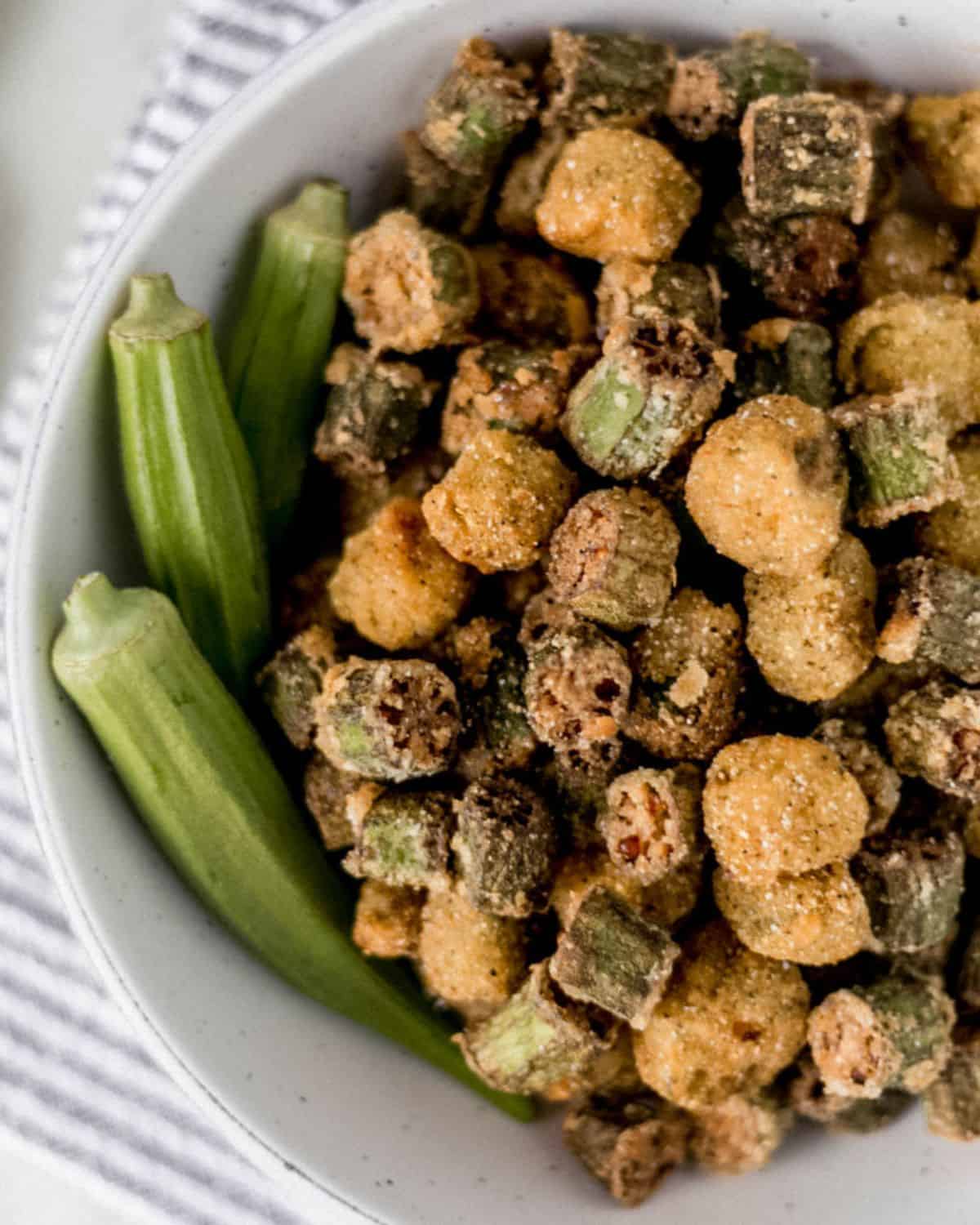 Close up view of fresh and fried okra in white bowl.