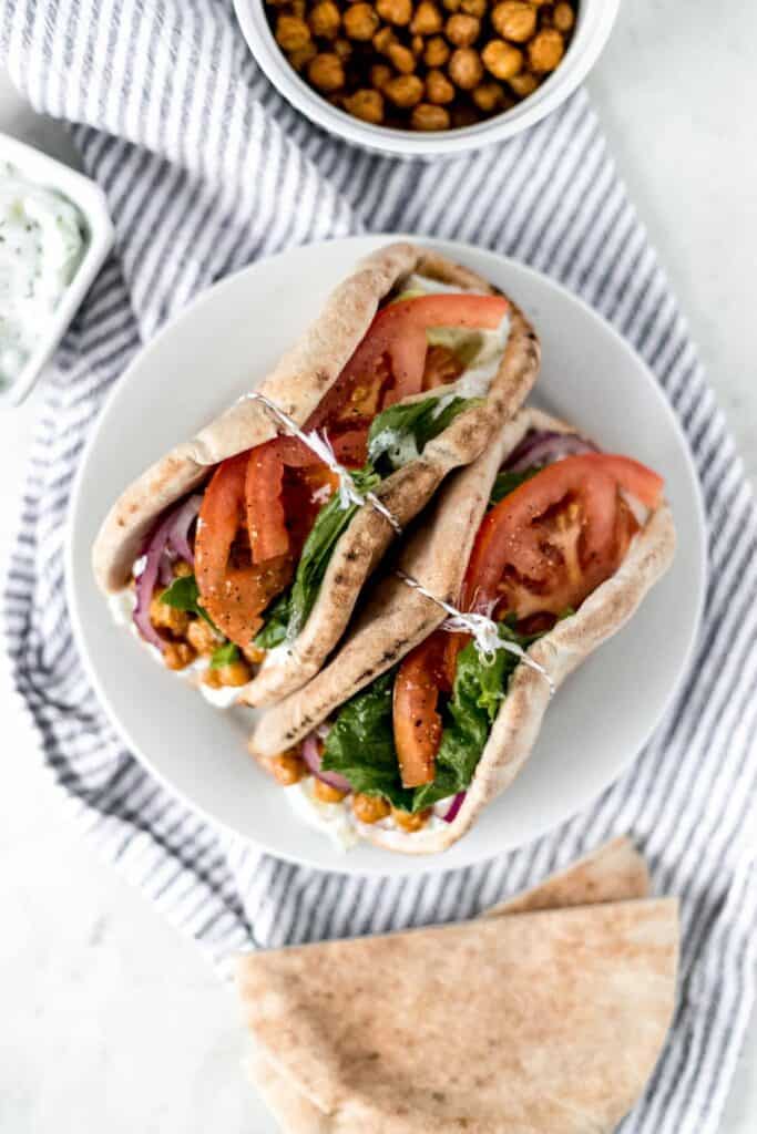 overhead shot of two spicy chickpea gyros on a plate with ingredients around it on a napkin