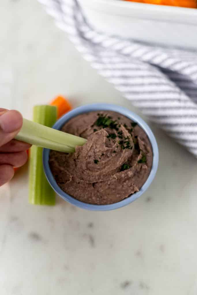 close-up side view of black bean dip with celery and carrots