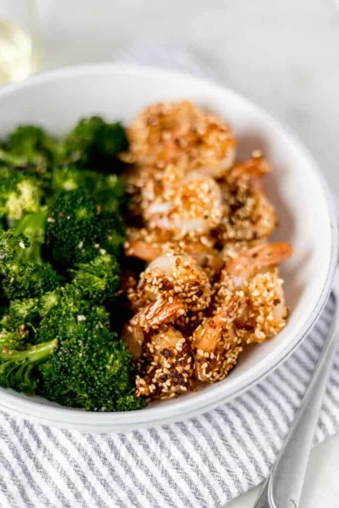 Sesame Shrimp and broccoli in a bowl on top of napkin with a fork