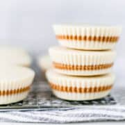 Close up front view of finished white chocolate peanut butter cups stacked on top of each other.
