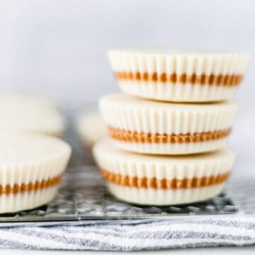 Close up front view of finished white chocolate peanut butter cups stacked on top of each other.