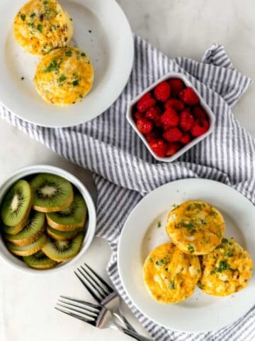 overhead view breakfast egg muffins on white plates with kiwi and raspberry