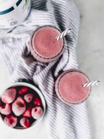 overhead view of strawberry smoothie with bowl of frozen strawberries